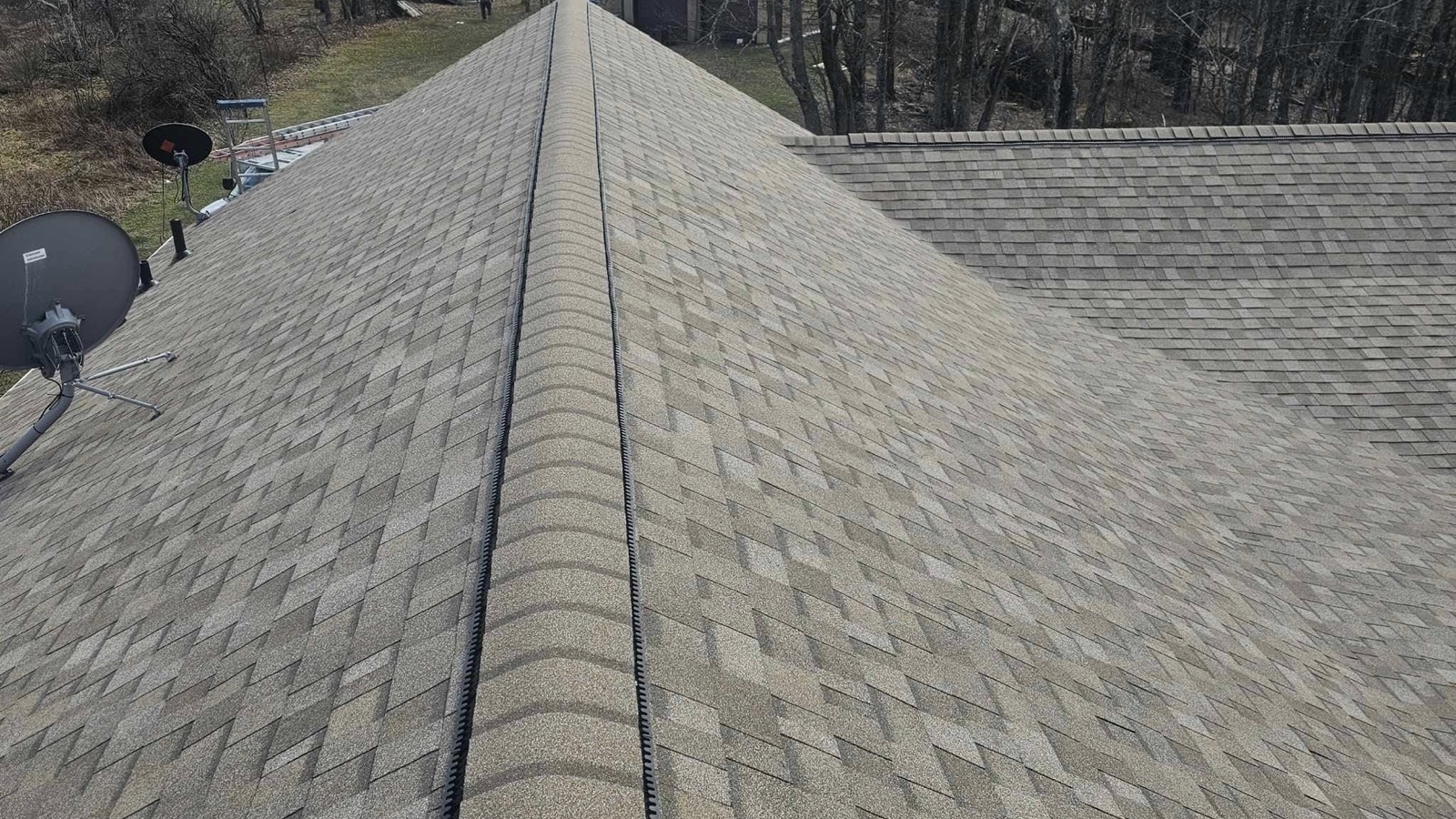 A newly shingled roof ridge with a ridge vent on a bare-tree winter day in Northeastern Pennsylvania
