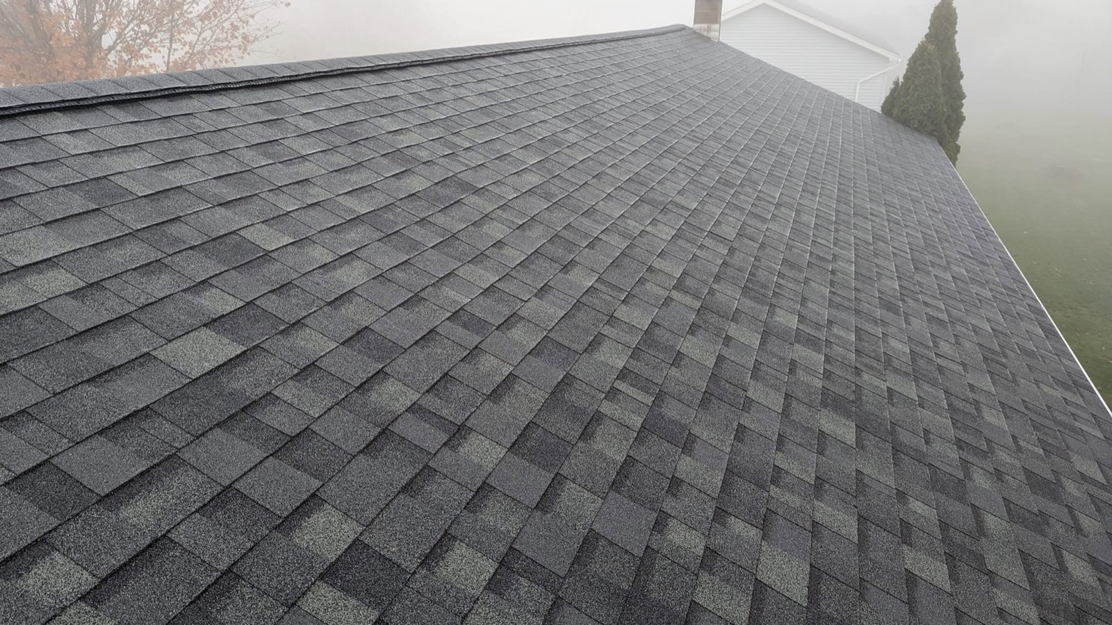 A dark asphalt shingle roof under heavy fog after a Pennsylvania storm